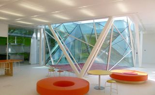 Bright white underground space with brightly coloured seating area positioned around central glass light well.