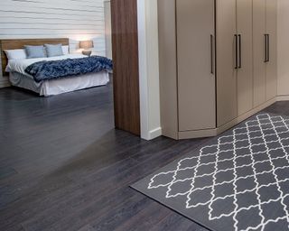 A bedroom with white shiplap walls, and concave taupe master closet design in adjacent room