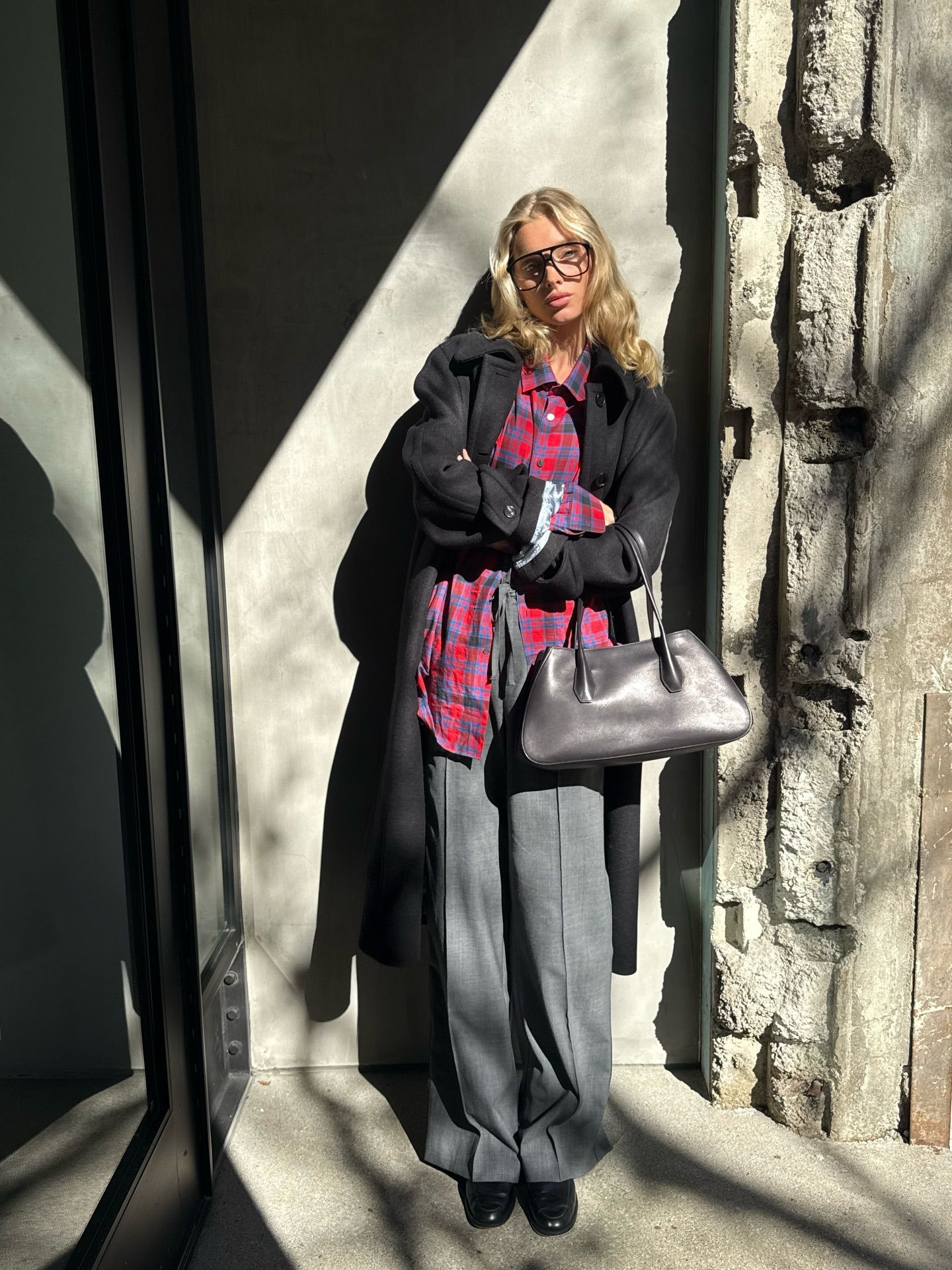 Elsa Hosk wearing a red flannel The Row shirt with a black jacket and gray tailored trousers.