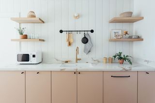 modern peach cottage kitchen with wooden shelves and white shiplap walls