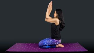 A woman yoga teacher in vajrasana garudasana posture isolated on black background