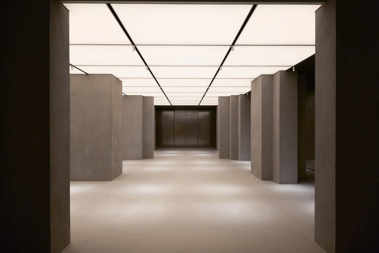 A cinematic museum room features paneled, lit-up ceilings inspired by the 1980s and brutalist pillars in grey.