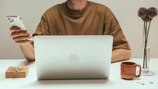 Man in front of computer and holding smartphone
