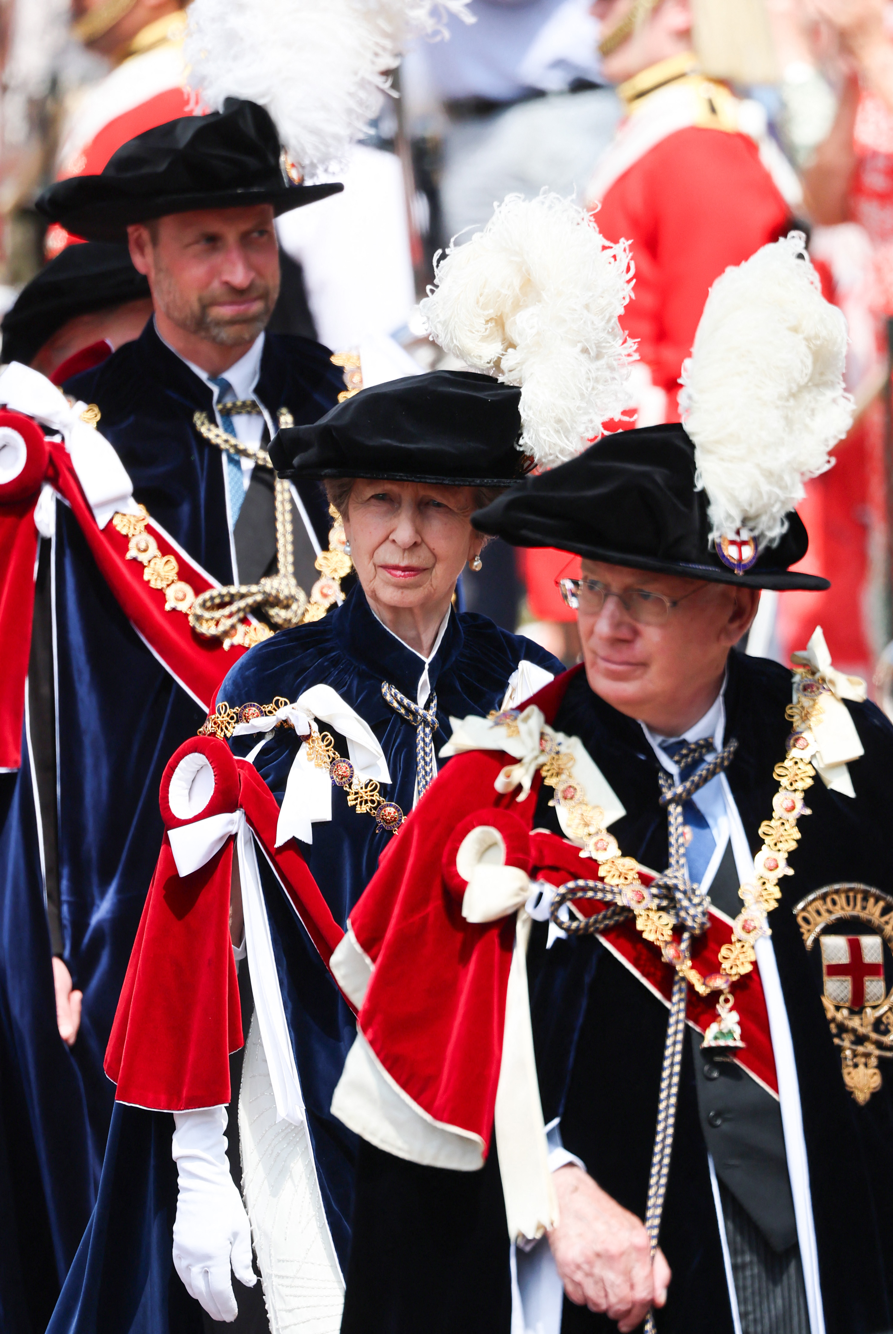Prince William walking behind Princess Anne and the Duke of Gloucester in robes and feathered hats