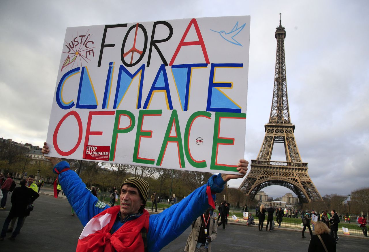 A demonstrator advocates for climate change solutions as global leaders work to finalize a historic agreement nearby.