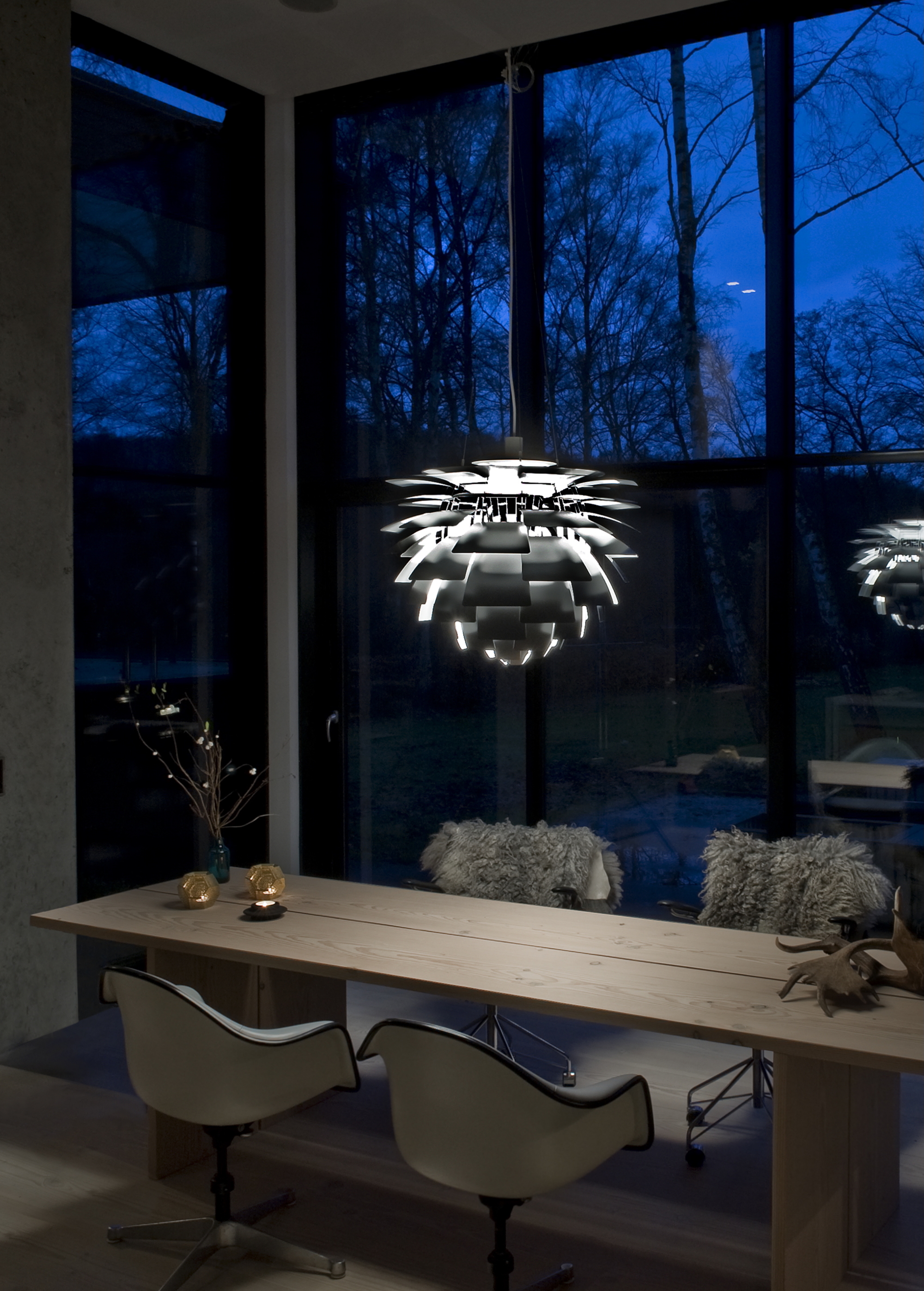 louis poulsen artichoke light hanging over dining table with timber table, four dining chairs with furs, and nightscape outside