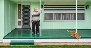 Dishevelled man stood on porch outside house
