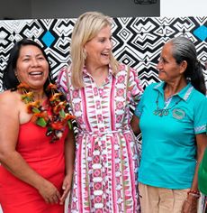 Duchess Sophie wearing a patterned shirt dress with her arms around three ladies and laughing