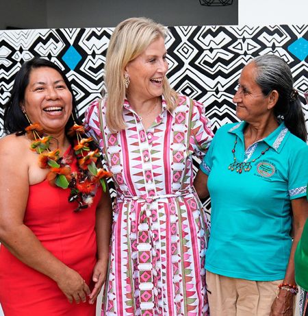Duchess Sophie wearing a patterned shirt dress with her arms around three ladies and laughing 