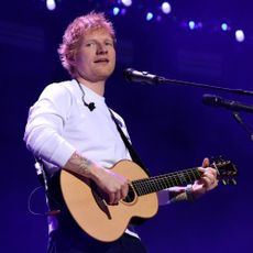 Ed Sheeran playing an acoustic guitar at a microphone
