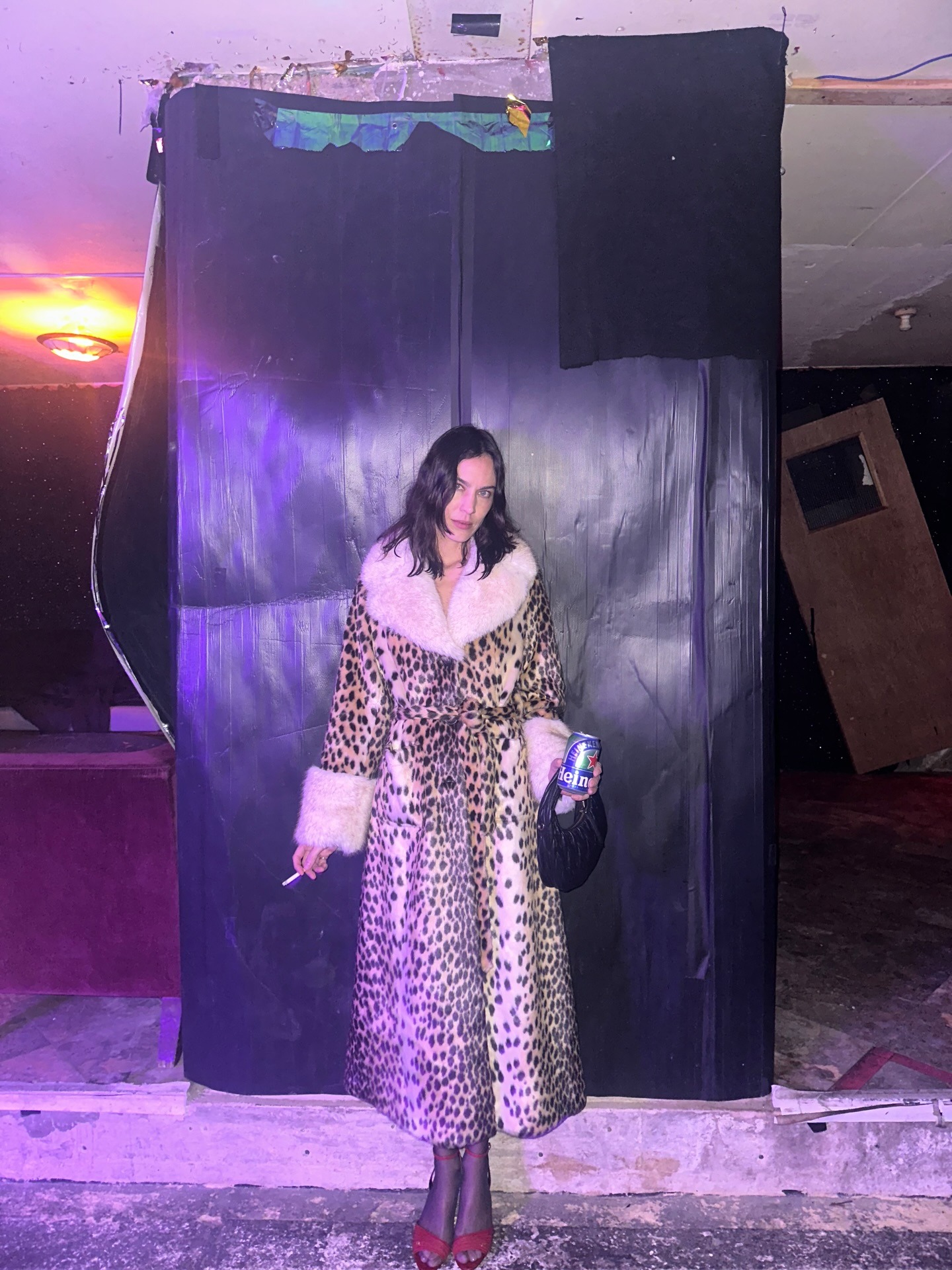 Alexa Chung wears the Queens of Archive Leopard print fur trimmed coat with red high heels and semi sheer tights.