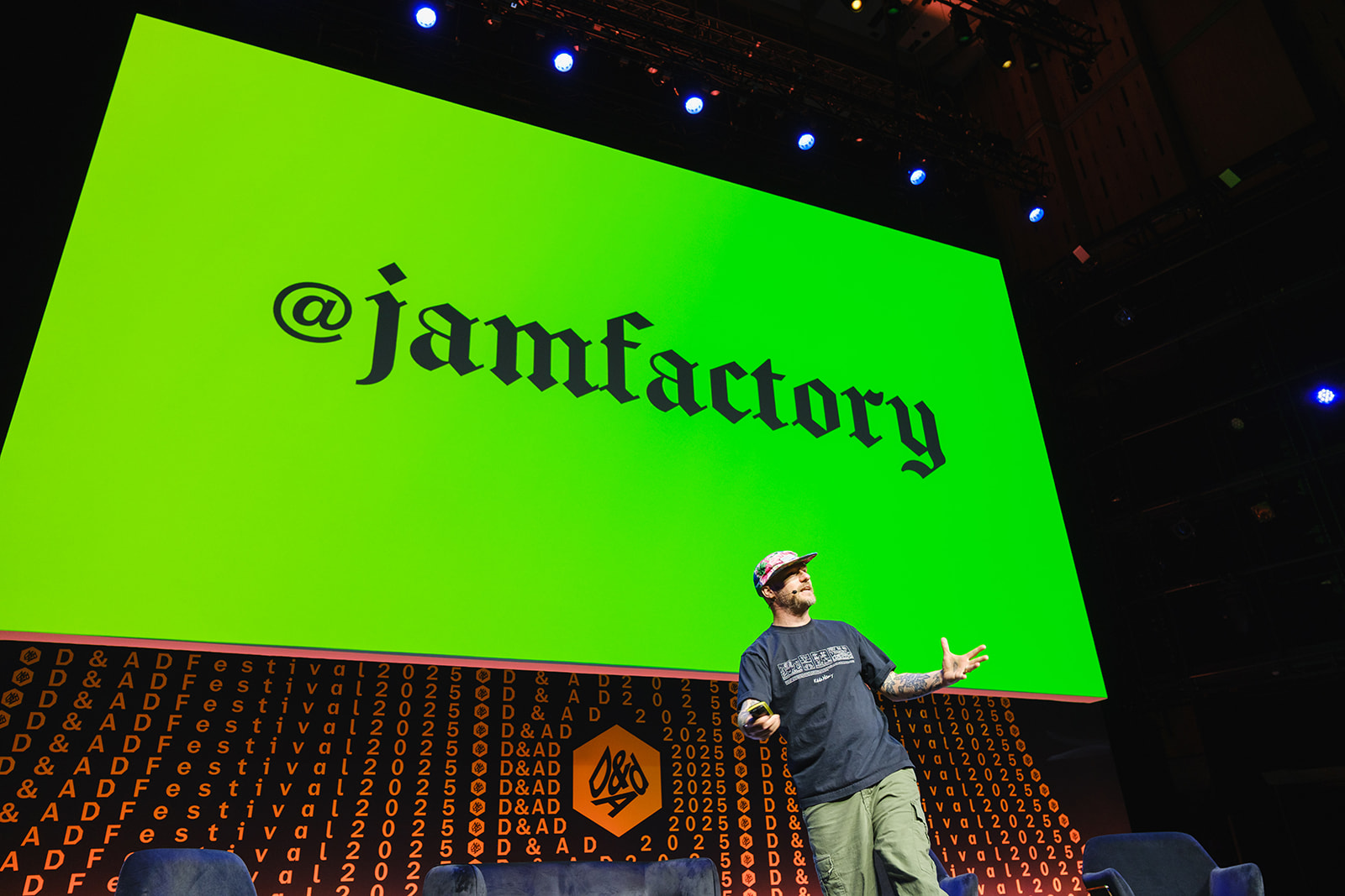 Gavin Strange on stage at D&AD Festival with bright colours behind him and a sign saying @jamfactory