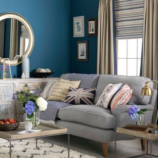 Blue living room with blinds and curtains on wall behind sofa