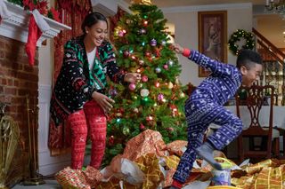 A still from 'Holiday Rush' of a mom and son playing around a christmastree