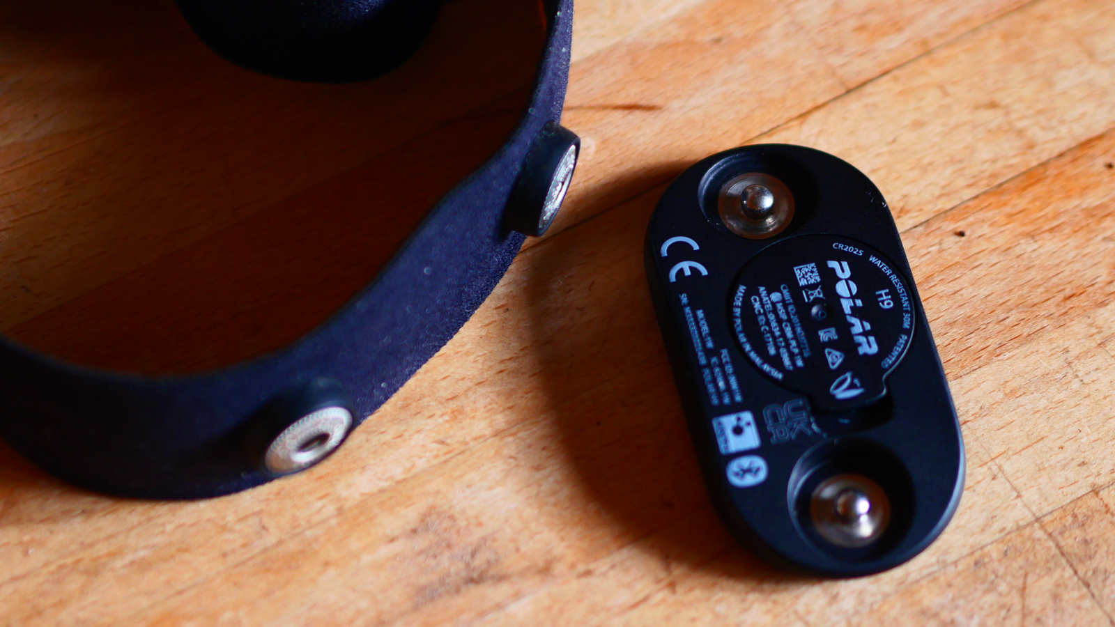 Polar H9 heart rate monitor on a wooden countr top showing how it attaches to the strap