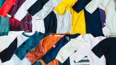 A range of multicoloured cycling jerseys laid out on a table, each overlayed over the one next to it