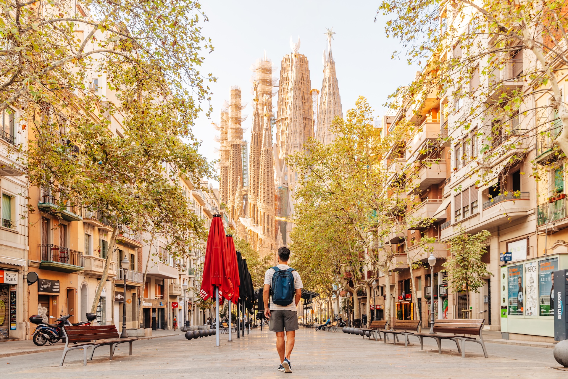 Man with backpack exploring streets of Barcelona, walking towards Sagrada Familia, Spain