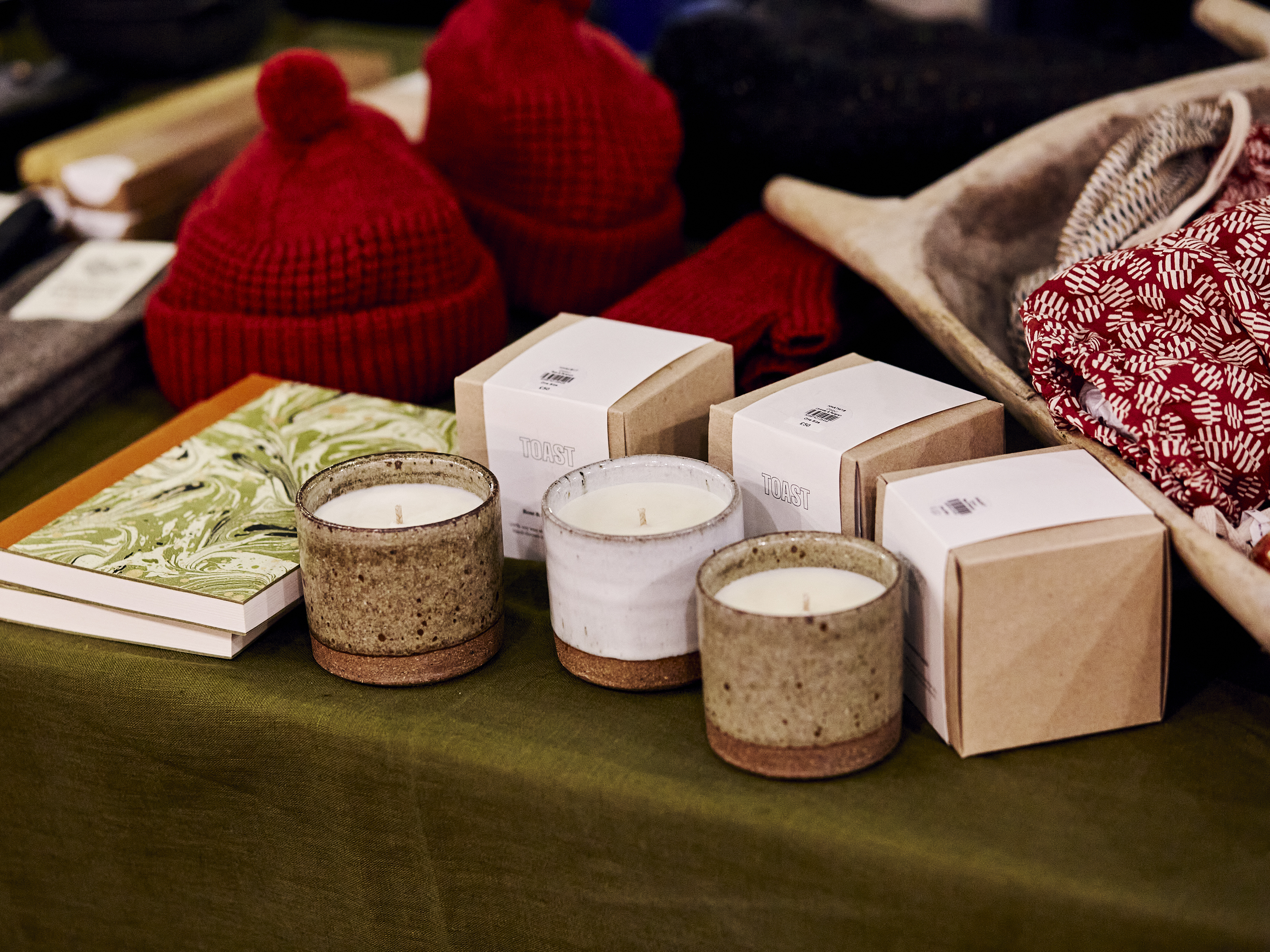 A market stall with wool goods, candles, and notebooks.