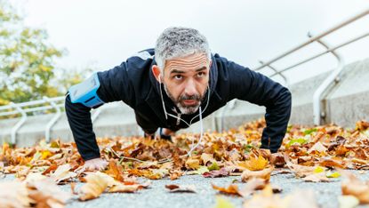 Man performing a push up outdoors wearing workout gear