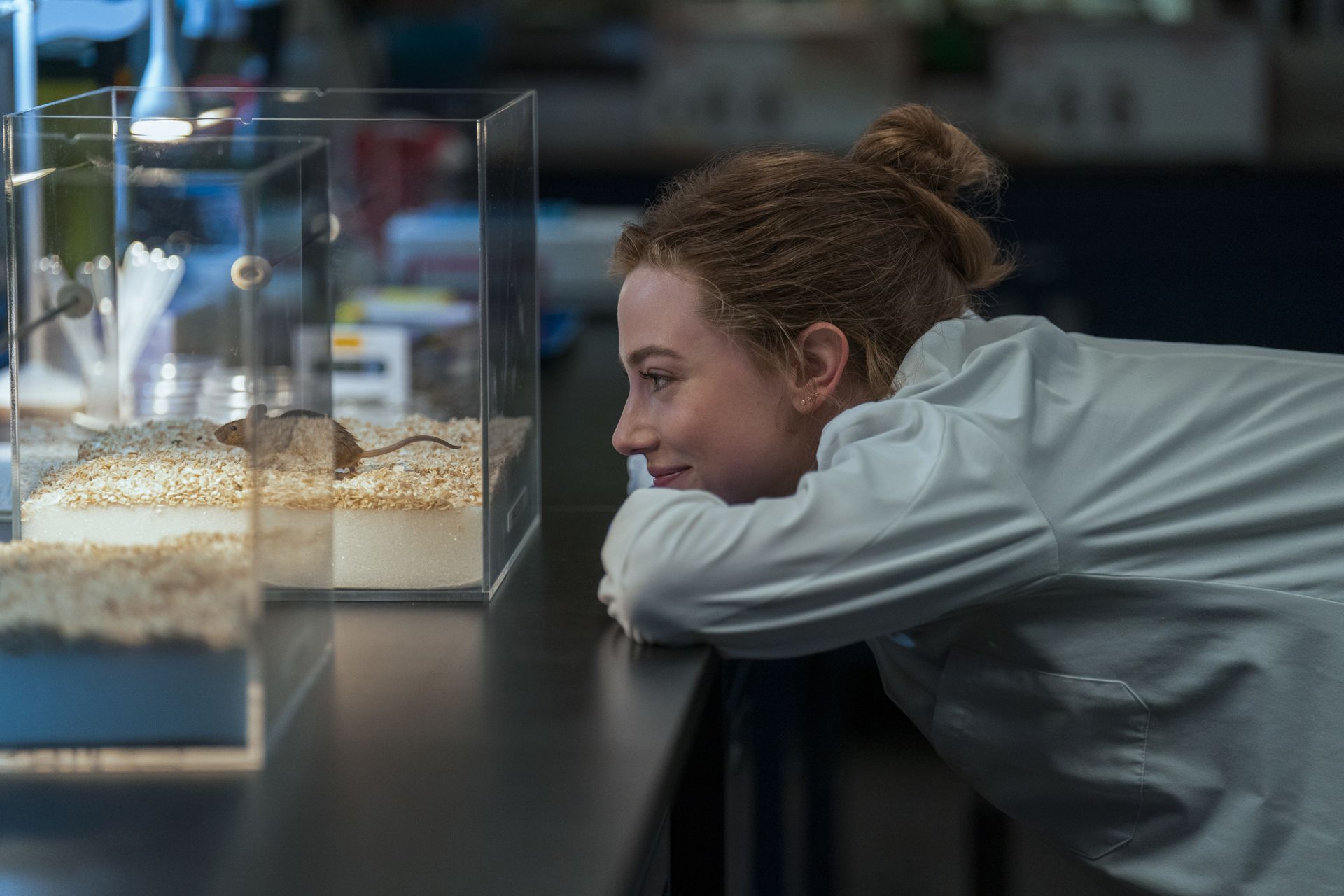 lili reinhart as olive wearing a lab coat looking at a mouse in a lab in the love hypothesis movie