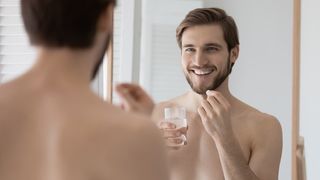 man looking in the mirror and taking a testosterone supplement