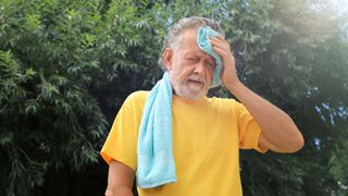 man with a towel round his neck suffering from heat stroke
