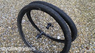 A pair of black gravel wheels and black tyres on a gravel pathway