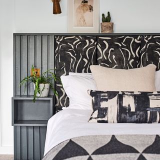 black and white patterned headboard behind bed with black and white bedding