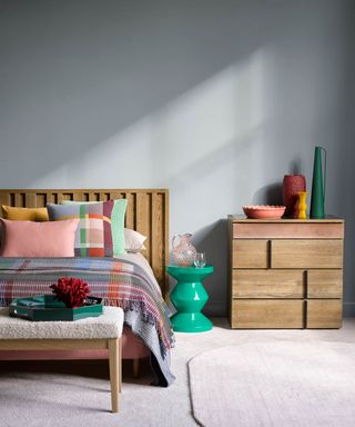 colors that go with light grey, light grey bedroom with modern wood bed and chest of drawers, multi coloured bedding and bed pillows, bright vases, cream carpet, green contemporary stool