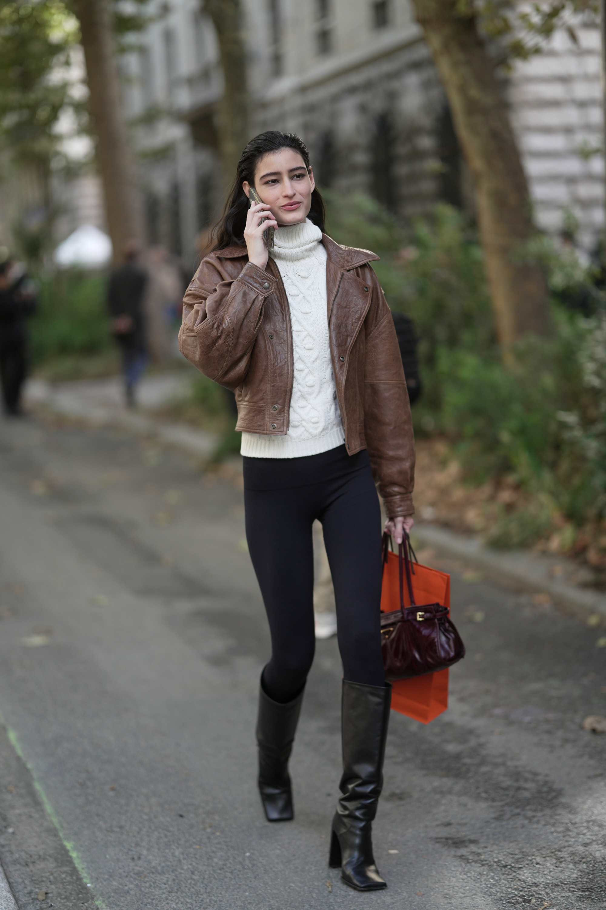 A woman in paris wears black leggings with knee-high black boots