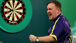 Luke Littler celebrates near dartboard after winning his World Darts Championship first-round match on 20 December 2023