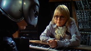 Paul Williams leans over in conversation with The Phantom at his keyboard in Phantom of the Paradise.