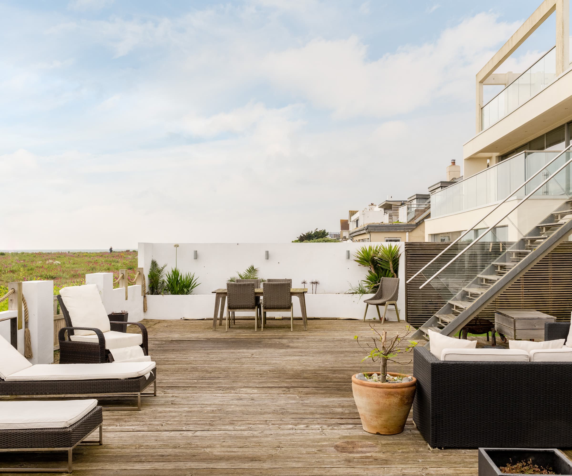 A balcony with white furniture and a metal staircase