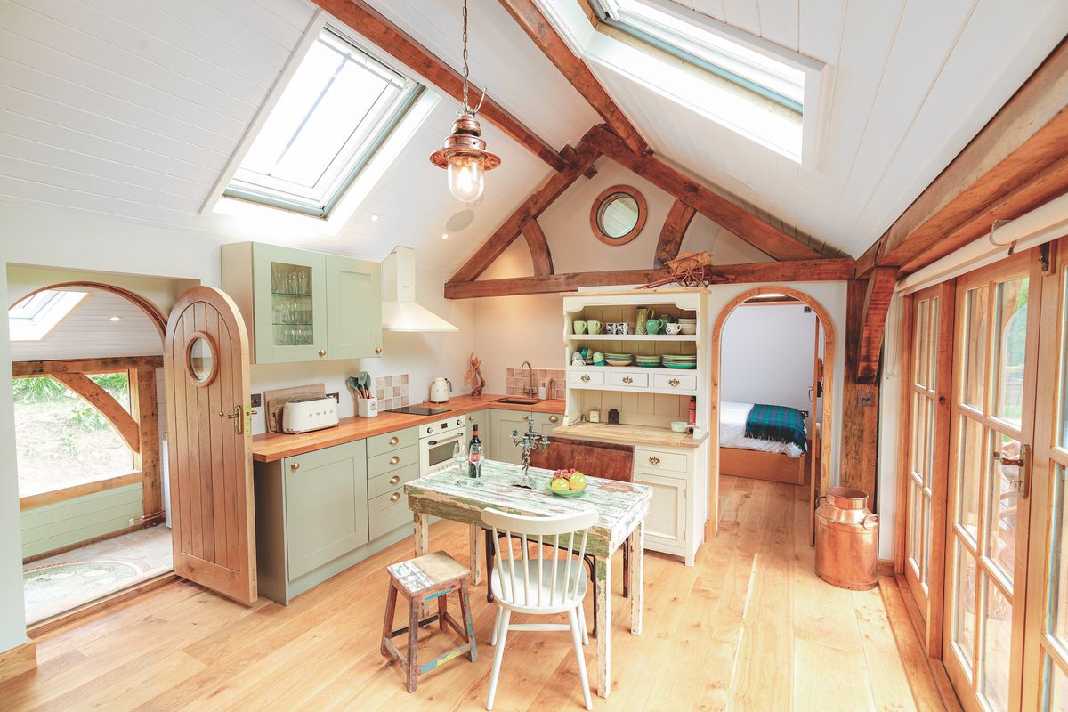 small green kitchen with dining table and vaulted ceiling