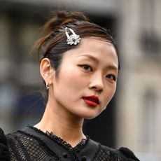 street style shot of woman wearing red lipstick with a bun and silver flower hairclip