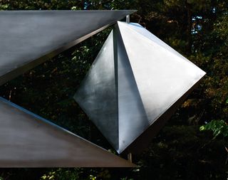 A diamond shaped stainless steel place inbetween the mouth of a stainless steel object