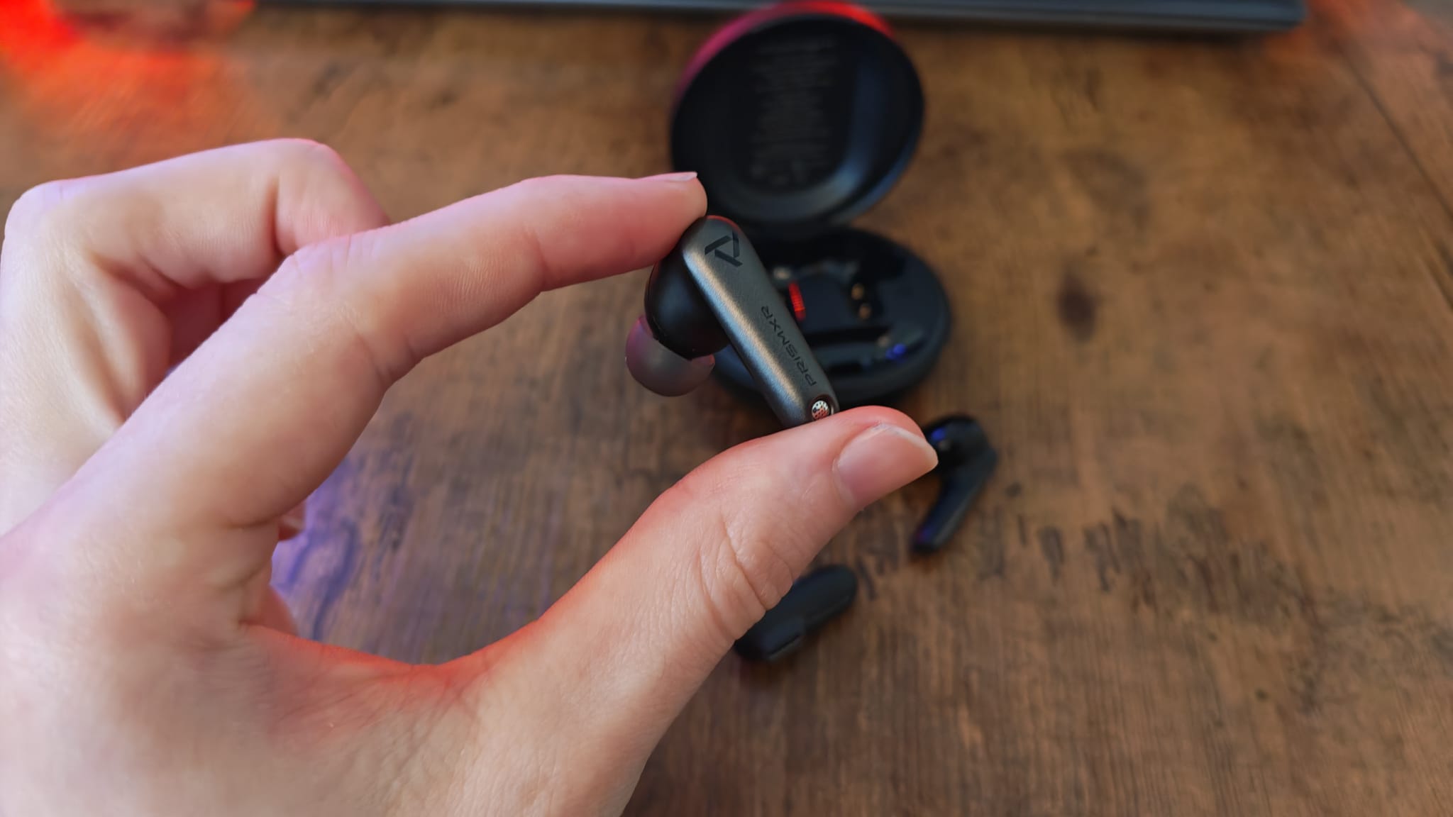 A reviewer holding the right PrismXR Vega T1 earbud
