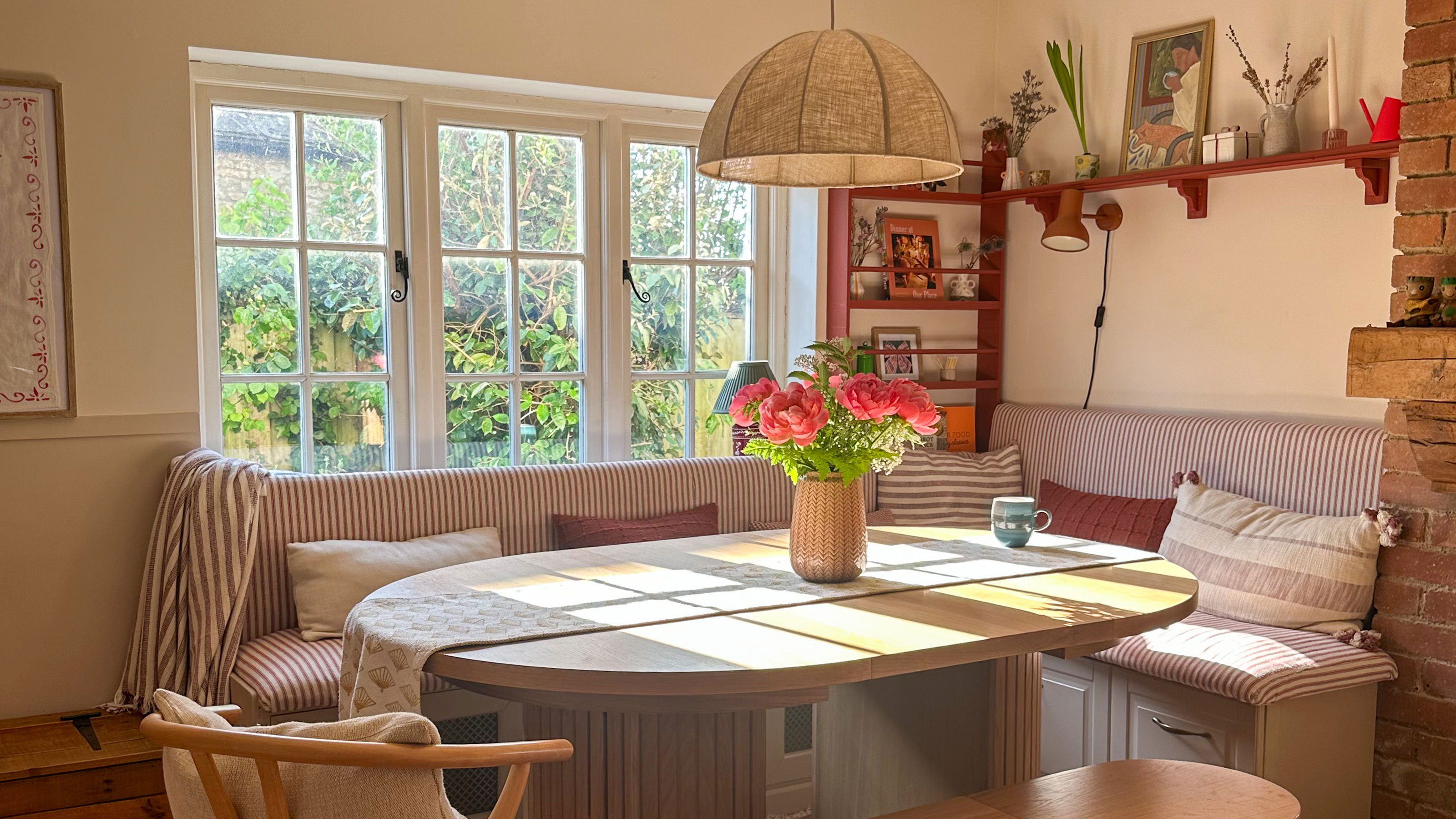 Neutral dining banquette corner with red and white striped seating upholstery
