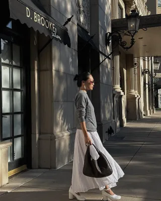 woman in grey sweater and white skirt