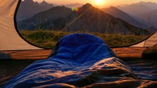 Legs in sleeping bag poking out of tent at sunrise