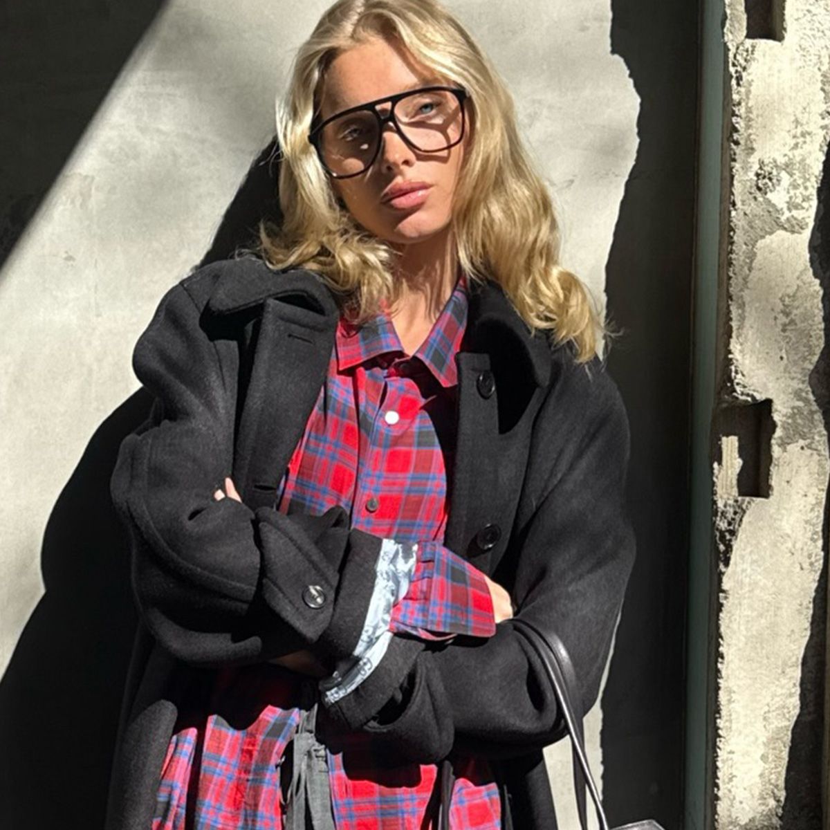 Elsa Hosk wearing a red flannel The Row shirt with a black jacket and gray tailored trousers.