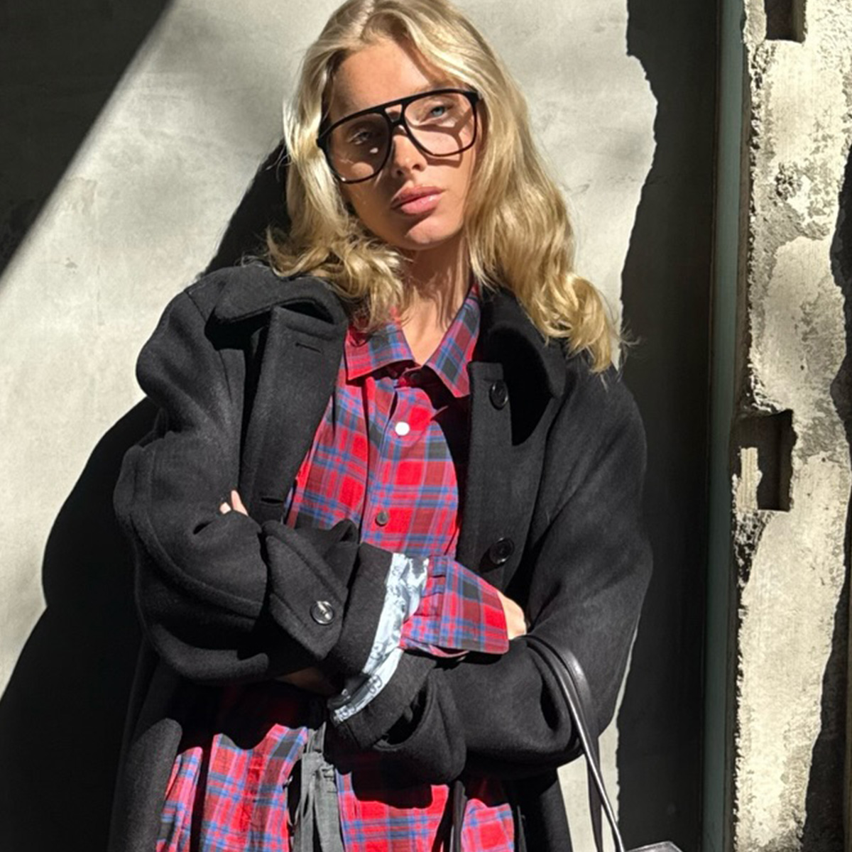 Elsa Hosk wearing a red flannel The Row shirt with a black jacket and gray tailored trousers.