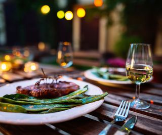 A late-night meal outdoors - steak and romano beans with a glass of white wine