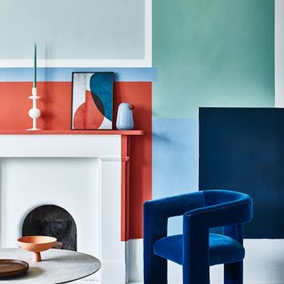 Wall painted in abstract colour blocks around white fireplace