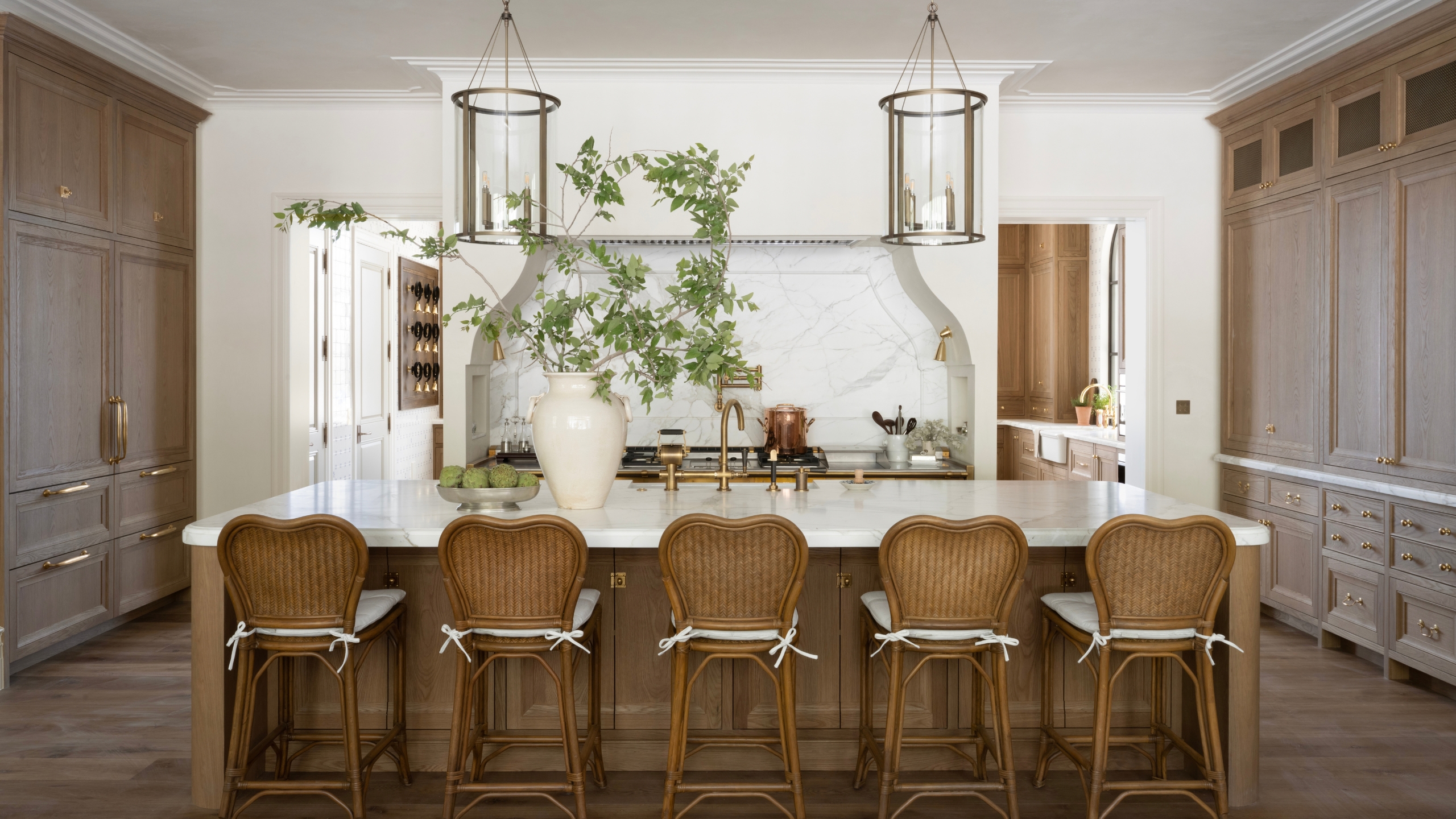 A large kitchen with dark wood cabinets, white walls, and marble countertops