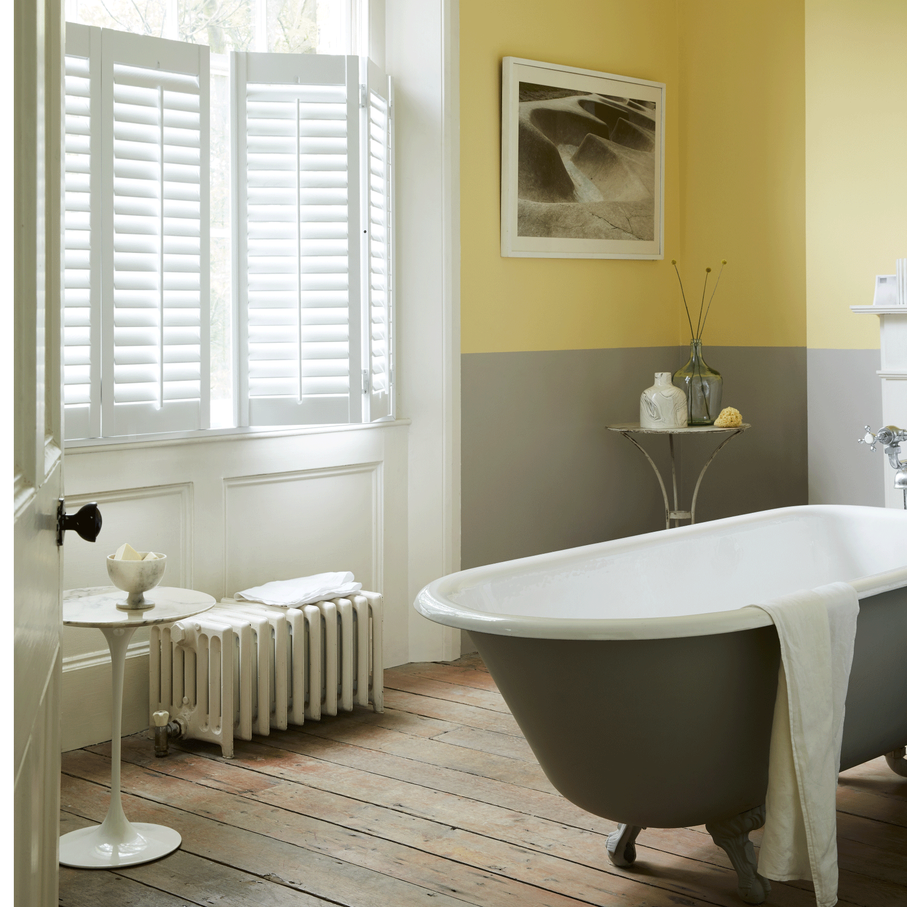 bathroom with yellow and grey wall bathtub white window and wooden flooring