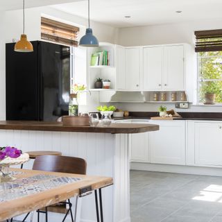 White open plan kitchen with dark wood worktops and grey floor