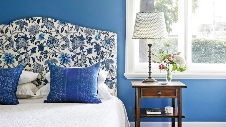 bedroom with blue walls and floral headboard designed by Sarah McPhee in Melbourne period home