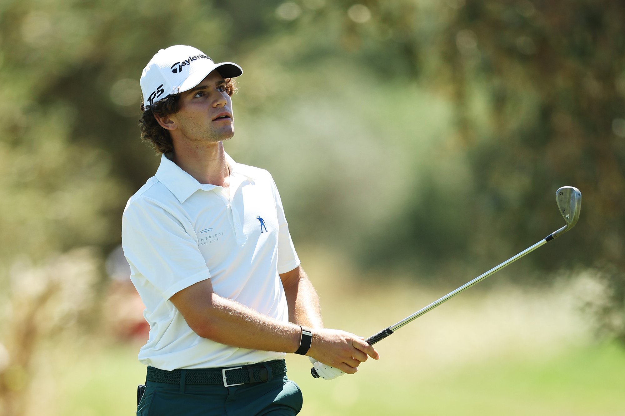 Angel Ayora in the finish position with a wedge after hitting a shot on the golf course, watching the ball in flight