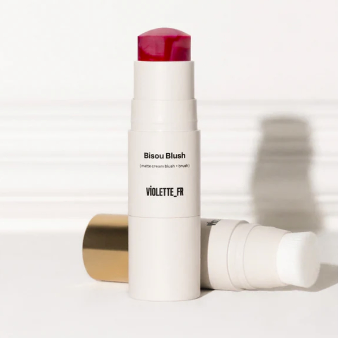 A product shot of the Violette_Fr Bisou Balm in the shade Maryam (a berry red) and the built-in brush, on a white-grey background
